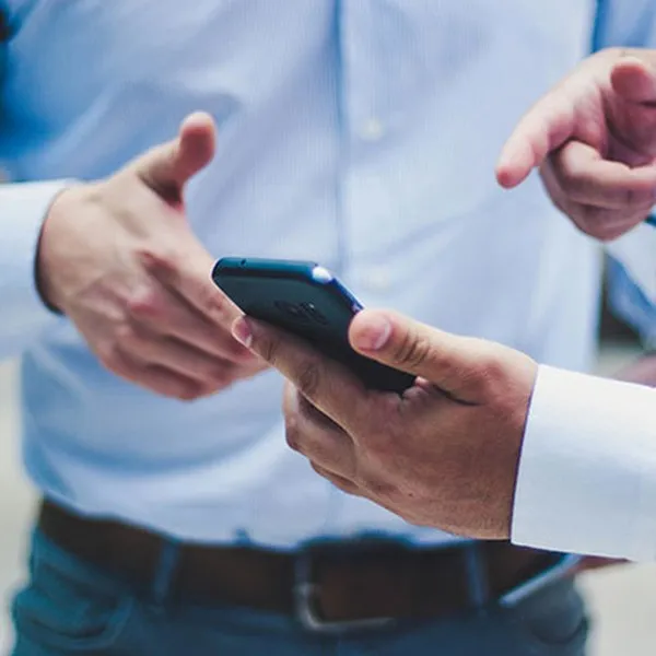 Deux personnes en chemise regardant ensemble un smartphone