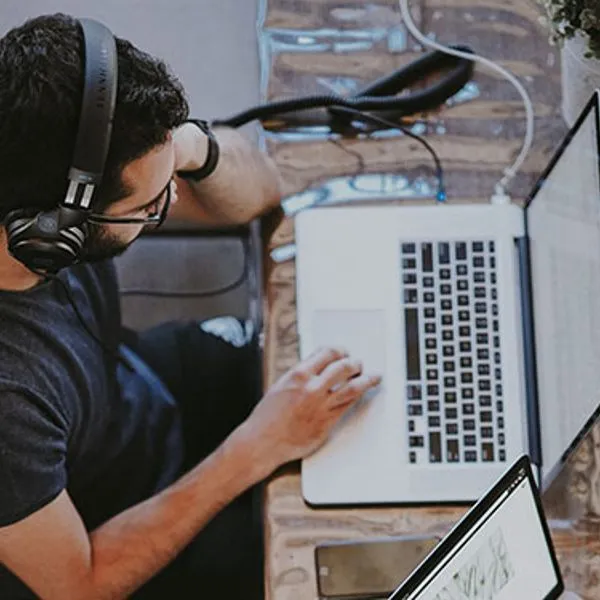 Un homme avec un casque travaillant sur un ordinateur portable, vu de dessus