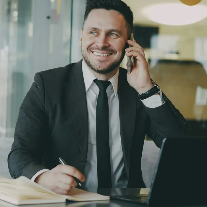 Un homme souriant en costume au téléphone à son bureau