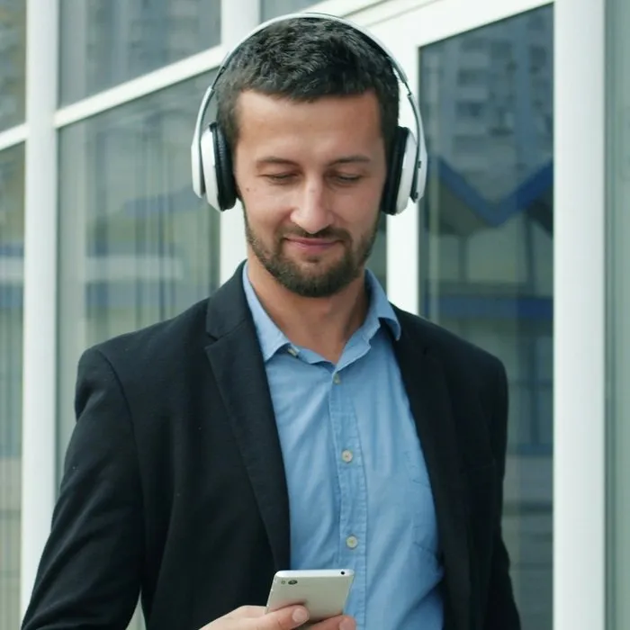 Un homme, un casque autour du cou, consultant son téléphone